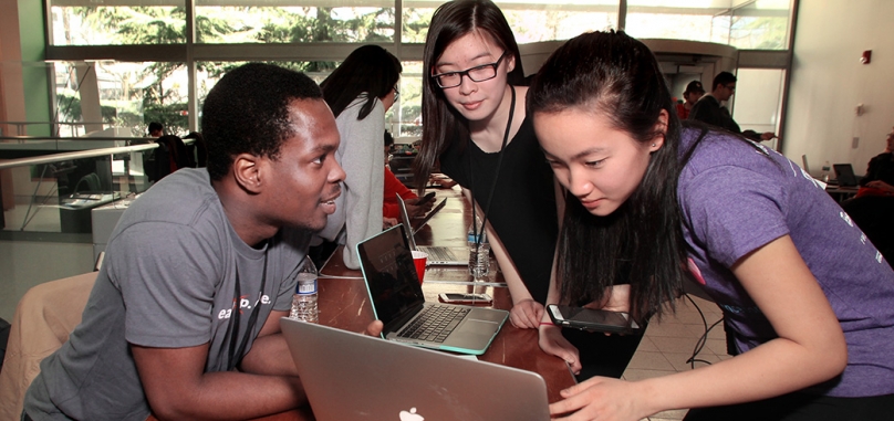 Three students gather around computer at the Hack Princeton event.