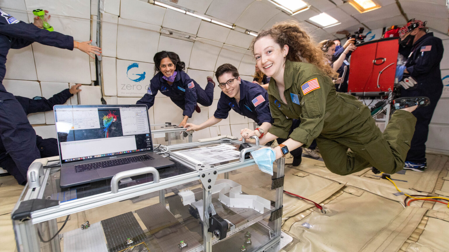 Radhika Nagpal with a team of researchers floating inside a test lab with equipment. 