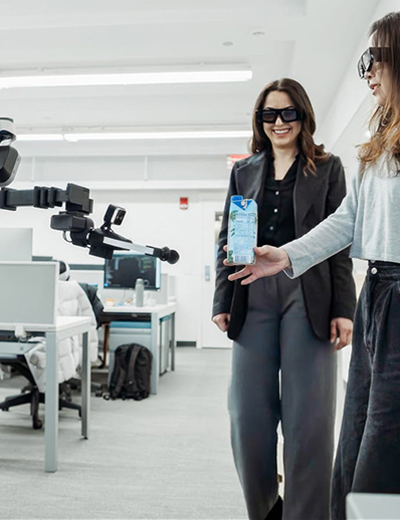 Two researchers standing around a robot wearing mixed reality headsets