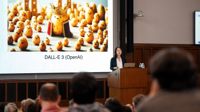 Danqi Chen speaking at a podium in front of an audience.  