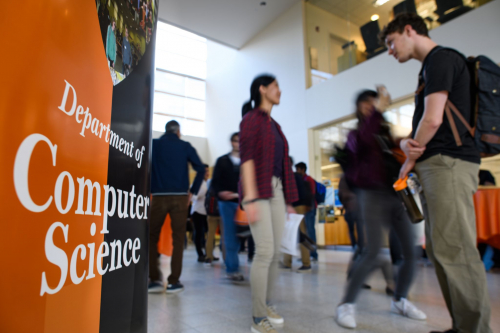 Students walking past a sign that says "Department of Computer Science." 