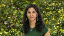 Radhika Nagpal wearing a green shirt in front of green foliage.