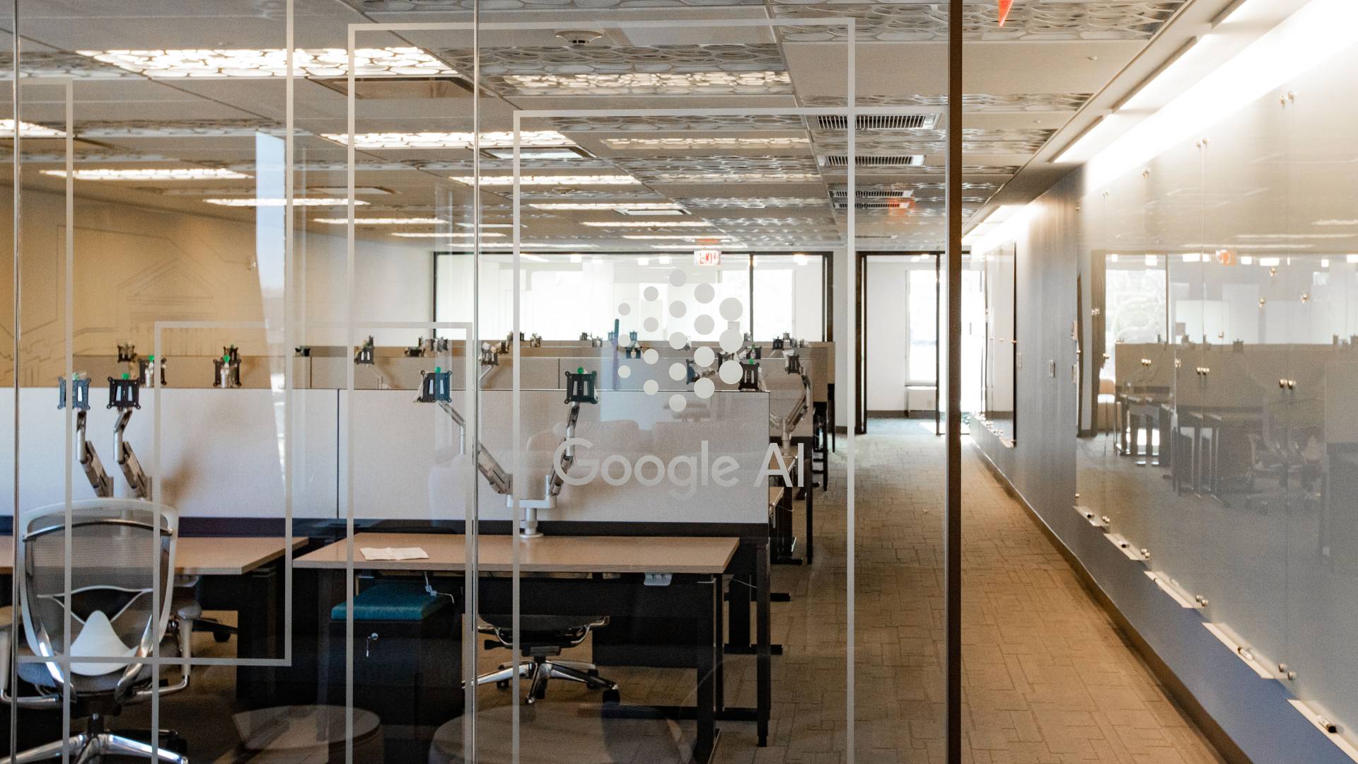 Office interior with desks in open floor plan. Google AI written on glass door.